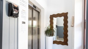 Un pasillo con un espejo grande, una planta en maceta y una puerta con cerradura digital.