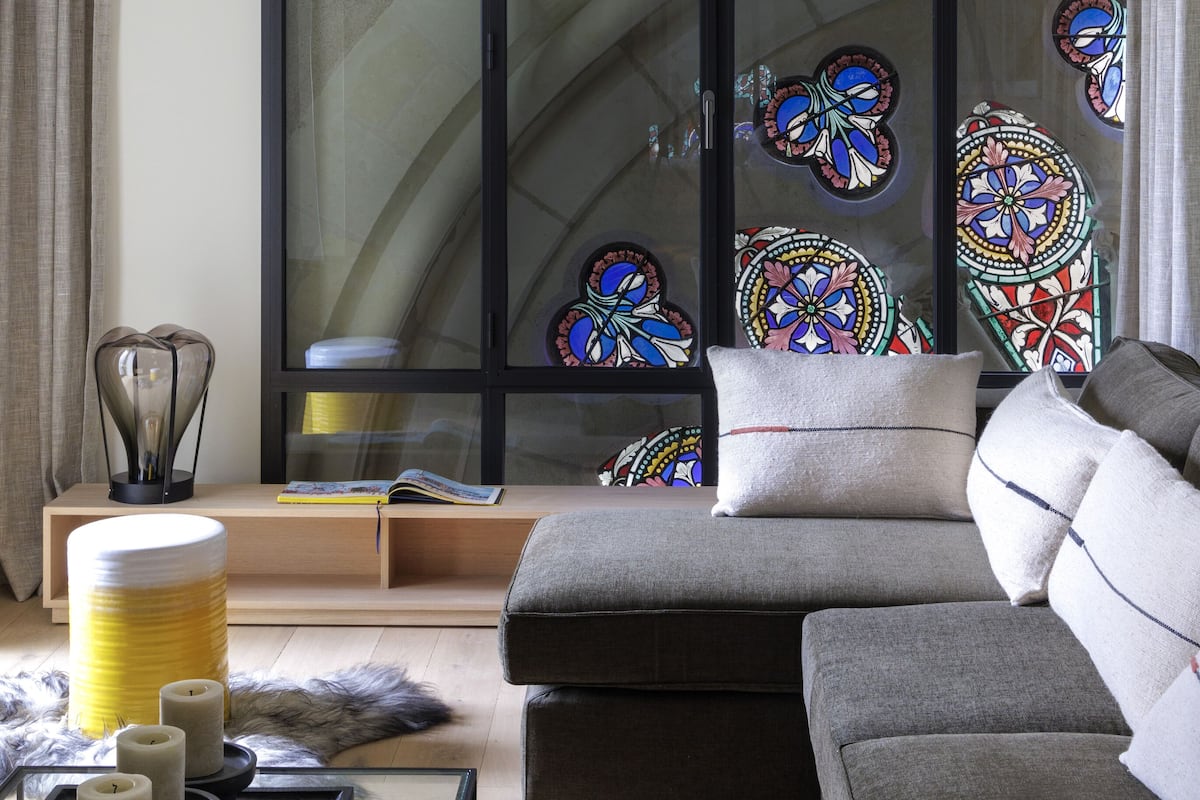 A modern living room with a grey sofa, a glass coffee table, and a decorative lamp.
