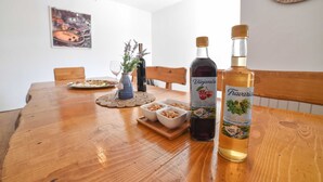 A wooden dining table with two bottles of wine, a plate of food, and a small plant. - Villa Bender (Dugopolje)