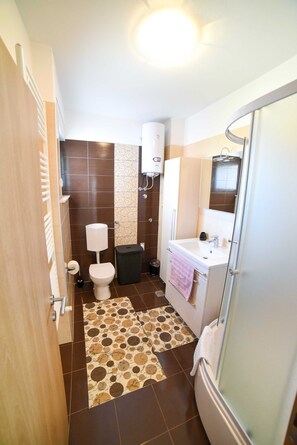 Un baño con inodoro, lavamanos y ducha.