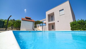 A modern building with a swimming pool, a covered area, and a staircase leading to an upper level. - Villa Bender (Dugopolje)