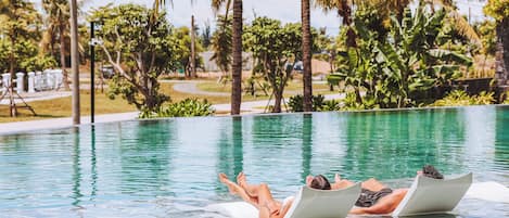 Una piscina al aire libre, sillones reclinables de piscina