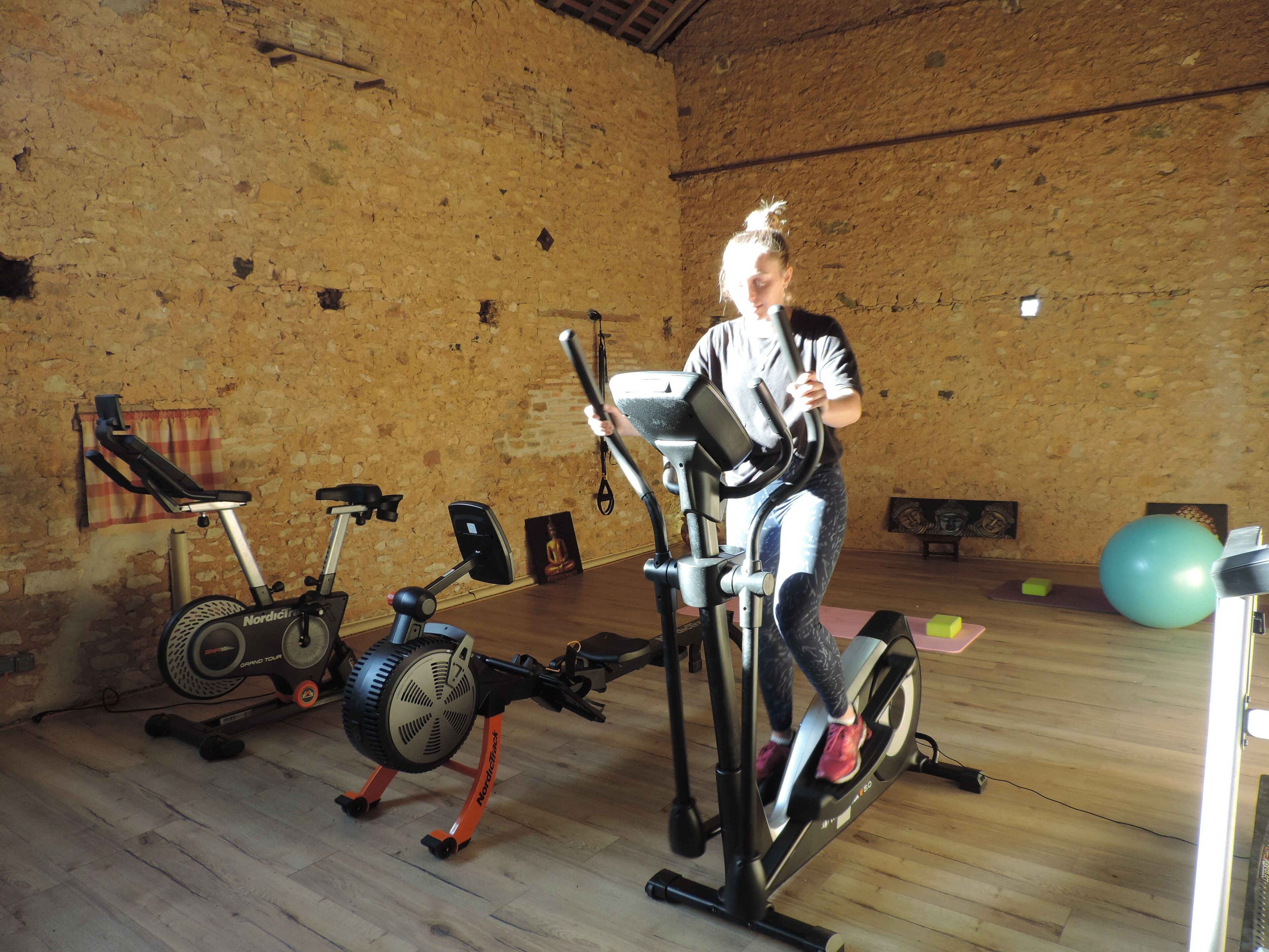 Une salle de sport équipée de matériel d’exercice, notamment des vélos d’appartement et un appareil de type elliptique.