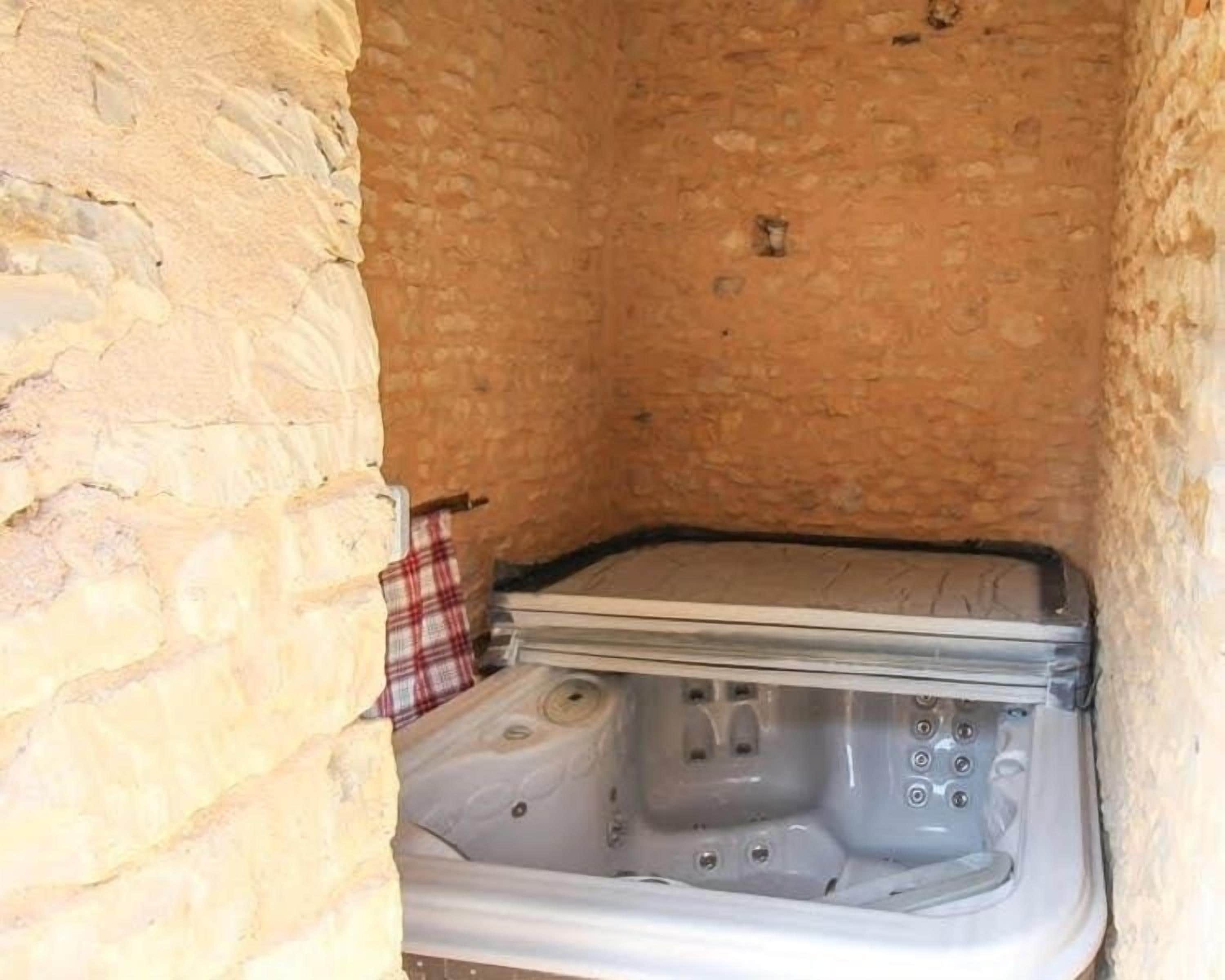 Un baño pequeño con paredes de piedra y una bañera.