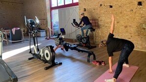 A gym with exercise equipment, a wooden floor, and a brick wall.