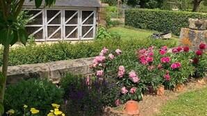A garden with a variety of flowers, a small shed, and a stone wall.