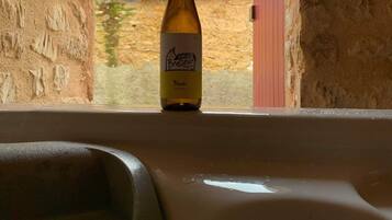 A bottle of Brasseur Blonde beer in a bathtub with a view of a stone building and a red door.