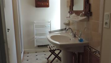 A bathroom with a sink, mirror, radiator, and tiled floor.