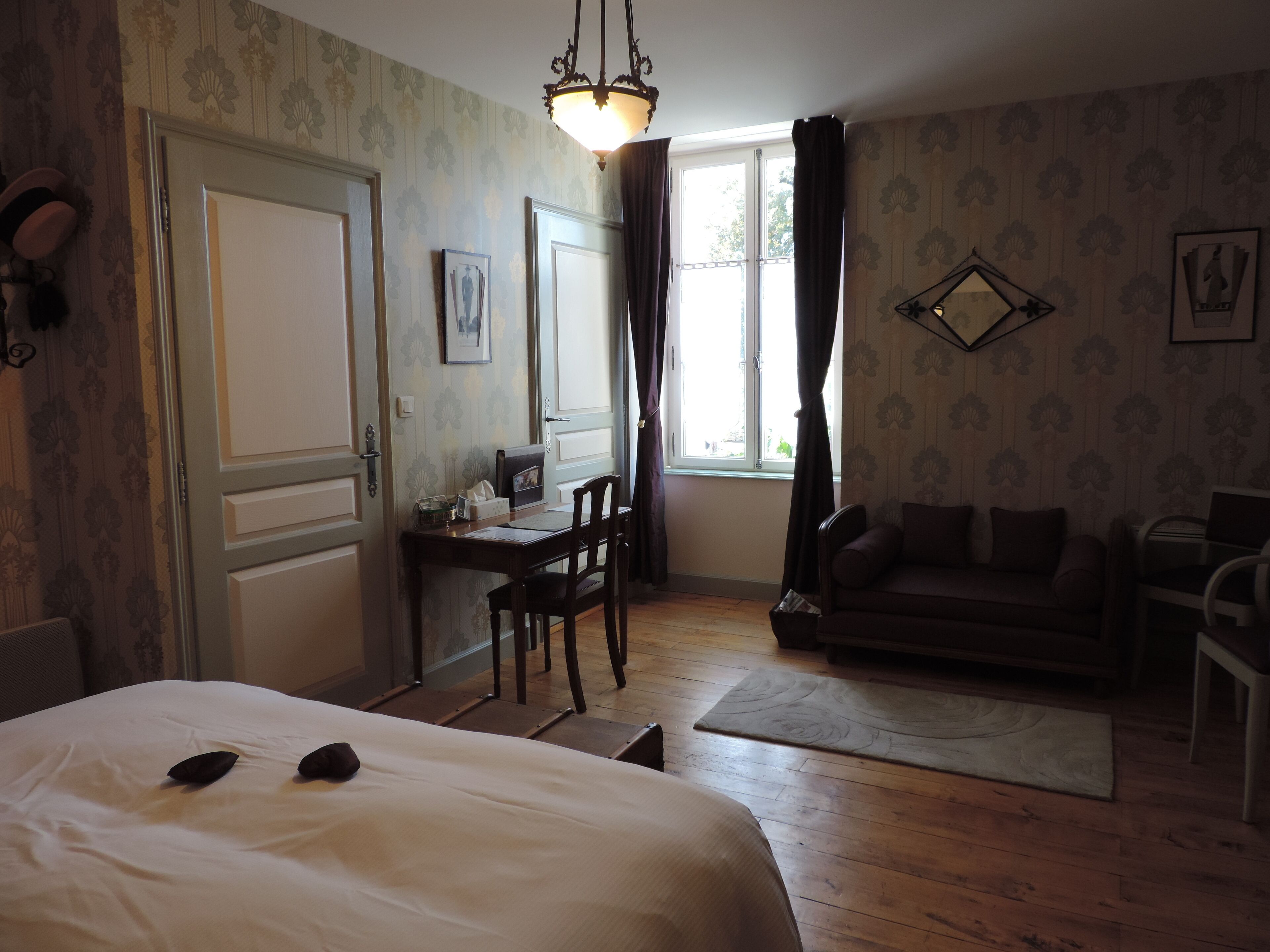 Ein Zimmer mit Bett, Schreibtisch, Stuhl, Sofa und einem Fenster mit Vorhängen.