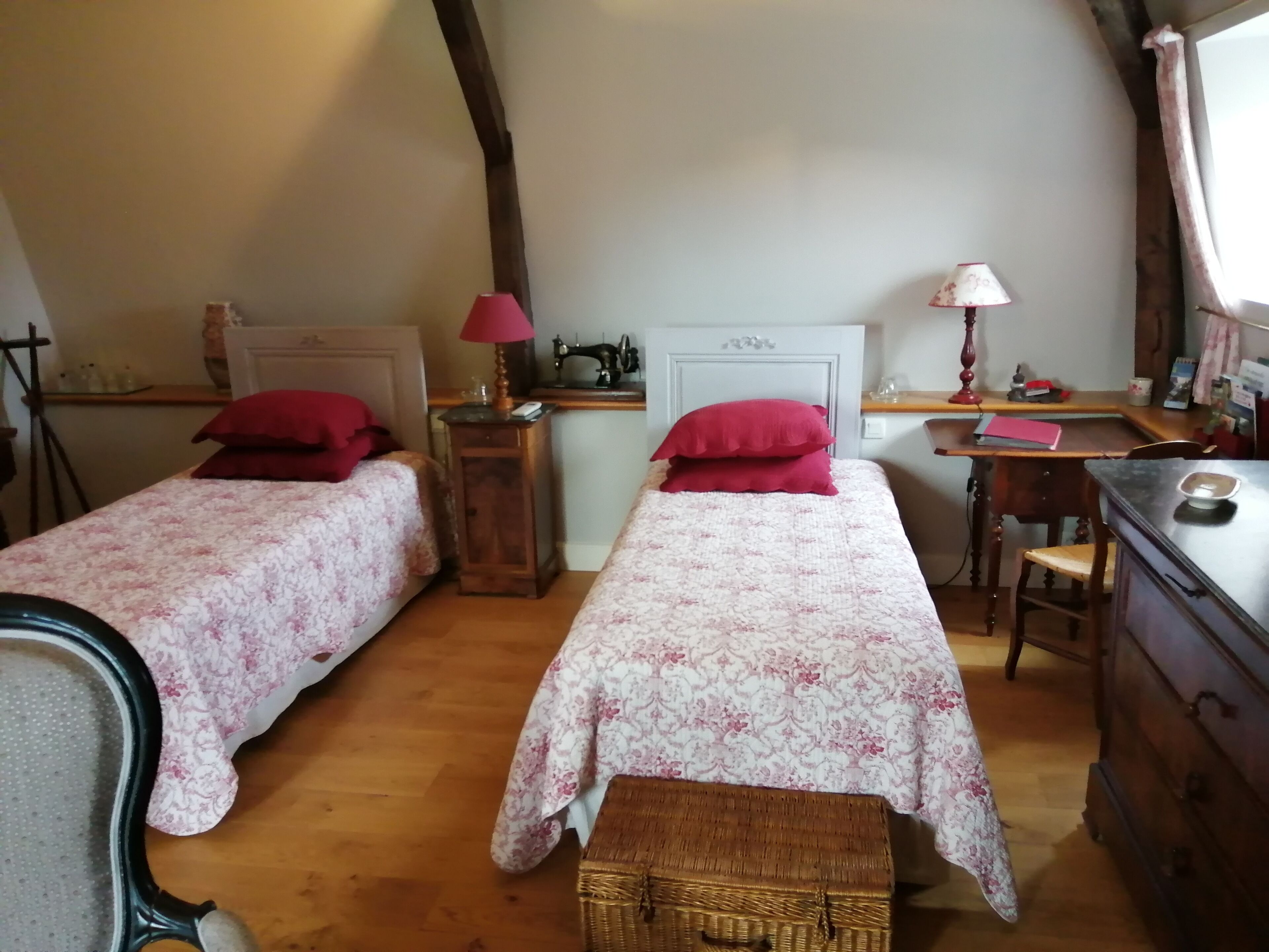 A bedroom with two beds, a desk, a chair, a dresser, and a lamp.