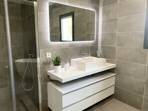 A modern bathroom with a large mirror, a white sink, and a shower area. - LUXURIOUS ARCHITECT-DESIGNED VILLA with an INFINITY POOL and a VIEW OF THE FOREST (Belin-Béliet)