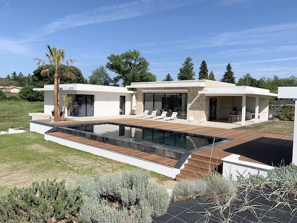 A modern house with a swimming pool, outdoor seating, and a view of the surrounding landscape. - LUXURIOUS ARCHITECT-DESIGNED VILLA with an INFINITY POOL and a VIEW OF THE FOREST (Belin-Béliet)