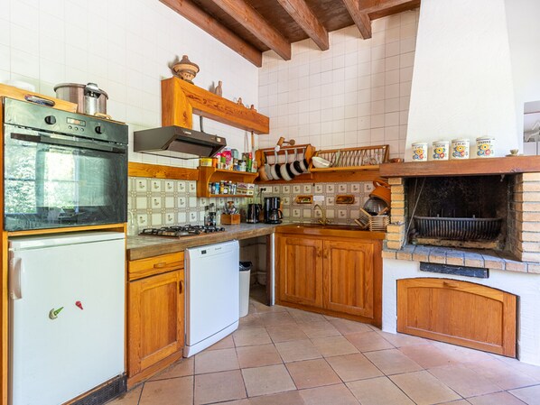 A kitchen with wooden cabinets, a stove, a dishwasher, and a brick oven.