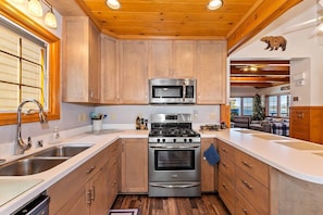 Eine Küche mit Holzausstattung, einem Edelstahlherd und einer Mikrowelle.