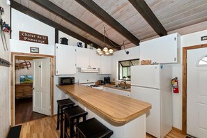 A kitchen with white cabinets, a wooden countertop, and a hanging light fixture. - Bear Ski Retreat by Destination Big Bear: Game Room! Cable TV! Close to Bear Mountain! Pet Friendly! (Big Bear Lake CA)