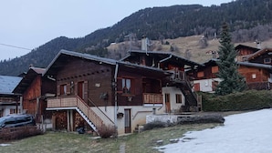 Un chalet in legno con un balcone, una scala e vista su una montagna innevata.