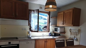 Una cucina con mobili in legno, una lavastoviglie Bosch, un forno a microonde e una finestra vista montagna.