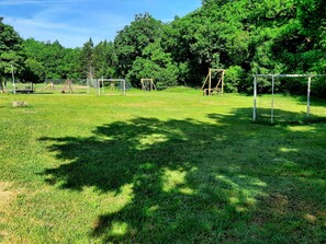 Children can play freely in this outdoor space surrounded by lush greenery and trees.