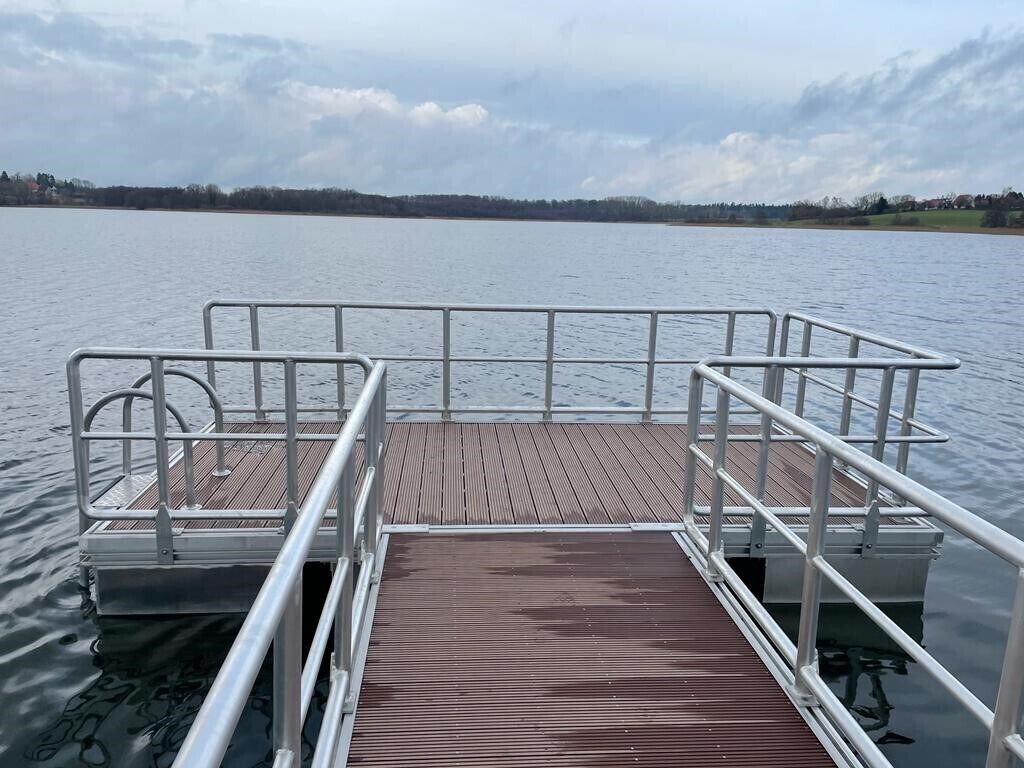 A wooden dock extending into calm water with a metal railing.