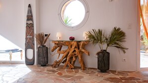 A lobby with a round mirror, a wooden table with a vase, and two potted plants. - Exceptional Corsican villa in the Gulf of Porto-Vecchio with its feet in the water (Porto-Vecchio)