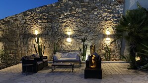 An outdoor seating area with stone walls, a sofa, and two chairs. - Exceptional Corsican villa in the Gulf of Porto-Vecchio with its feet in the water (Porto-Vecchio)