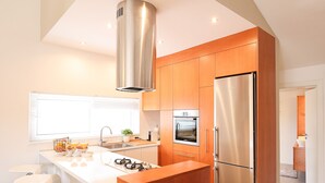 A modern kitchen with a central island, stainless steel appliances, and wooden cabinetry.