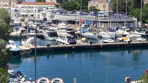 A marina with numerous boats docked, a bridge, and buildings in the background.