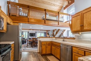 A spacious kitchen with wooden cabinets, a stainless steel refrigerator, and a built-in oven.