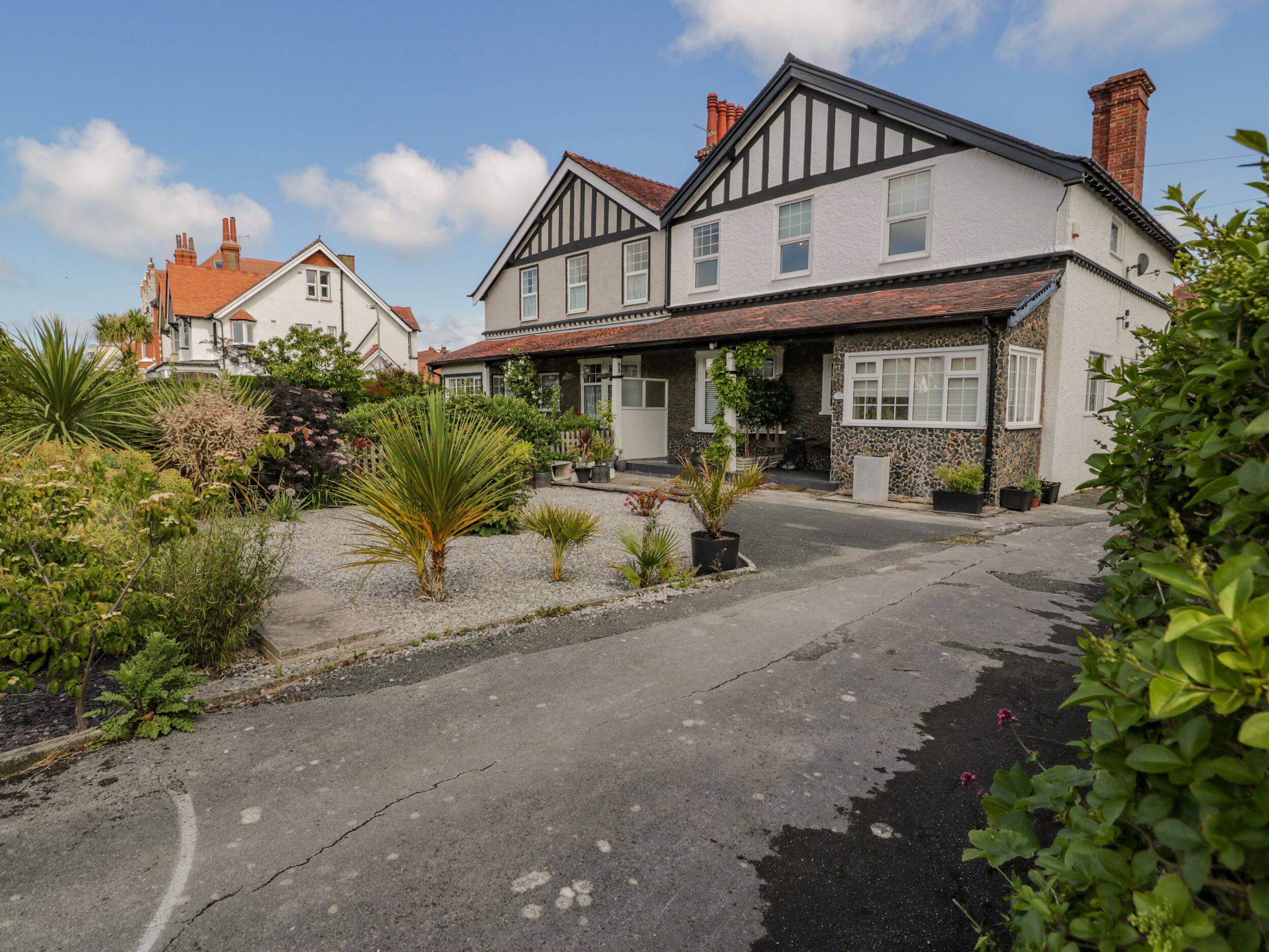 A two-story house with a stone facade, a tiled roof, and a driveway leading to a front door.
