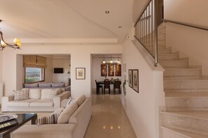 Ein modernes Wohnzimmer mit Sofa, Essbereich, Treppe und Kunstwerken an den Wänden.