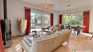 Een ruime woonkamer met een bank, een eettafel voor vier personen en een open haard.