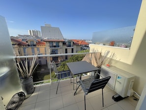 A balcony with a table and chairs, a potted plant, and an air conditioning unit. - Renovated studio with AC and wifi at Aiguillon port for 2 (Arcachon)