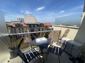 Enjoy a peaceful retreat on this balcony with a table and two chairs, offering a serene view of the surrounding residential area.