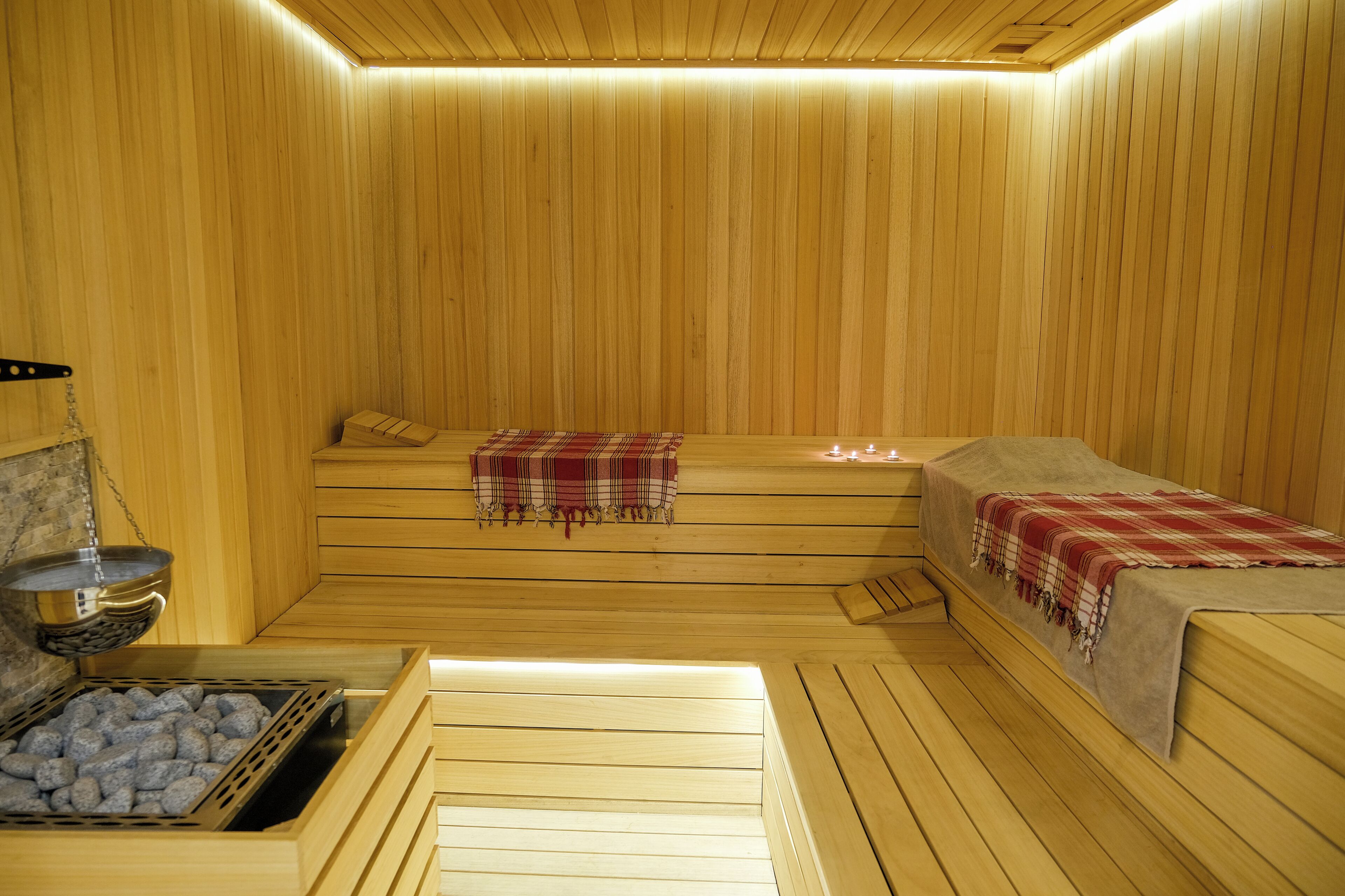 Een sauna met houten banken, een bank met een plaid en een bank met een handdoek.