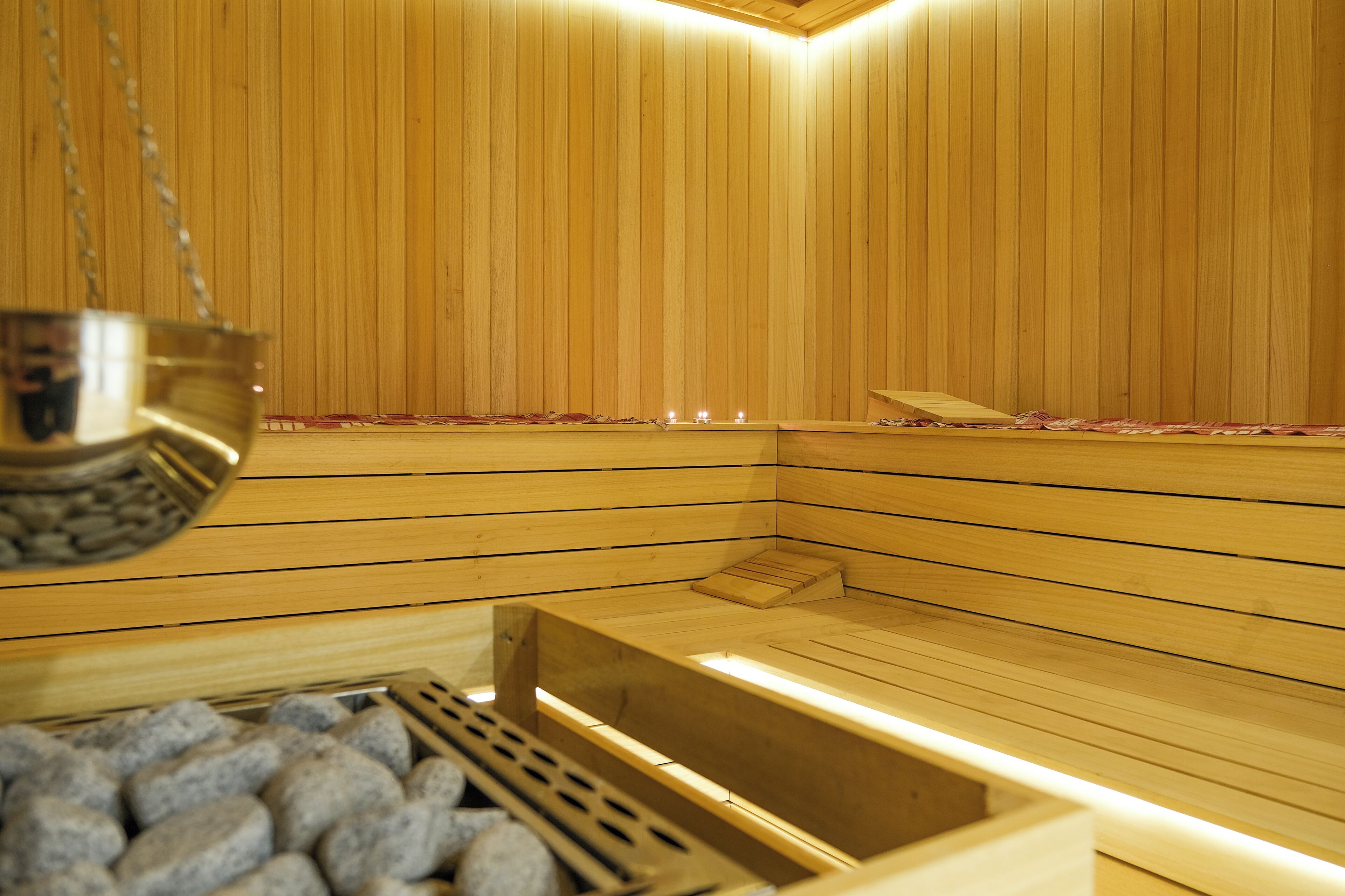A sauna with wooden walls, a bench, and a stone-filled container.