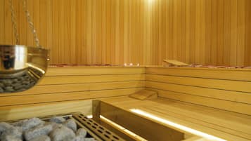 Eine Sauna mit Holzwänden, einer Sitzbank und einem steinbefüllten Behälter.