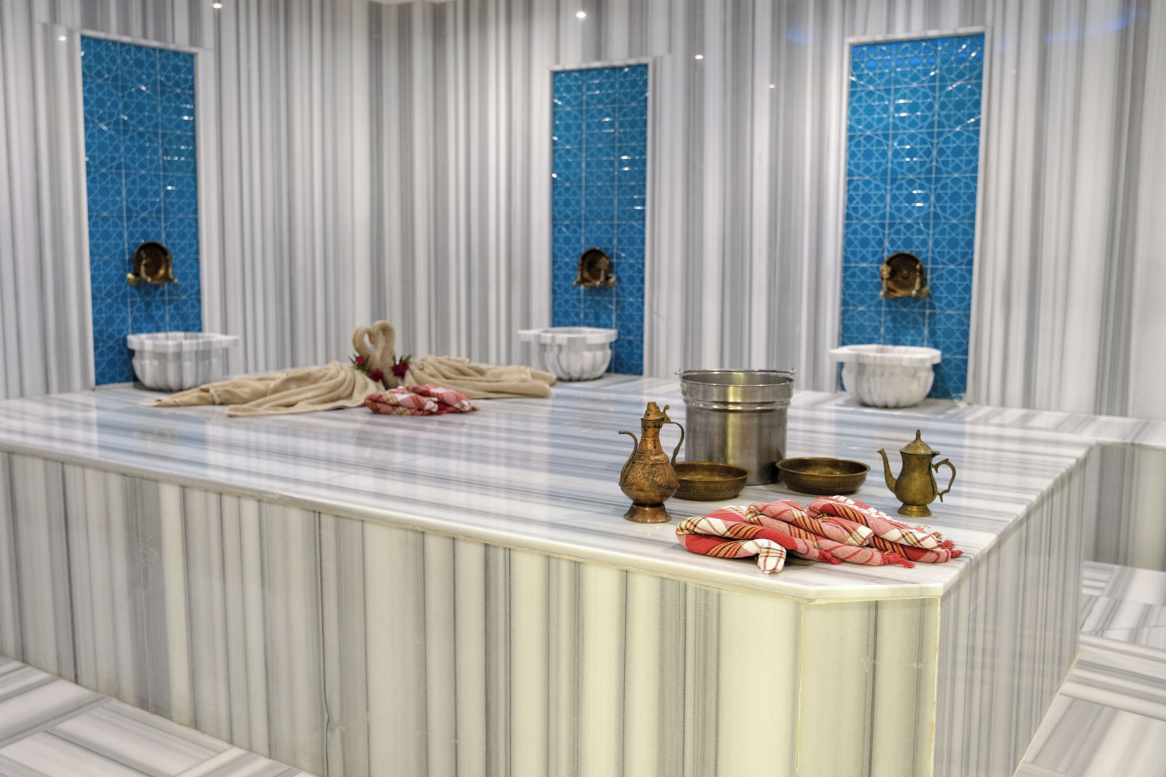 A marble bathroom with a large sink, two gold-colored basins, and a towel rack.