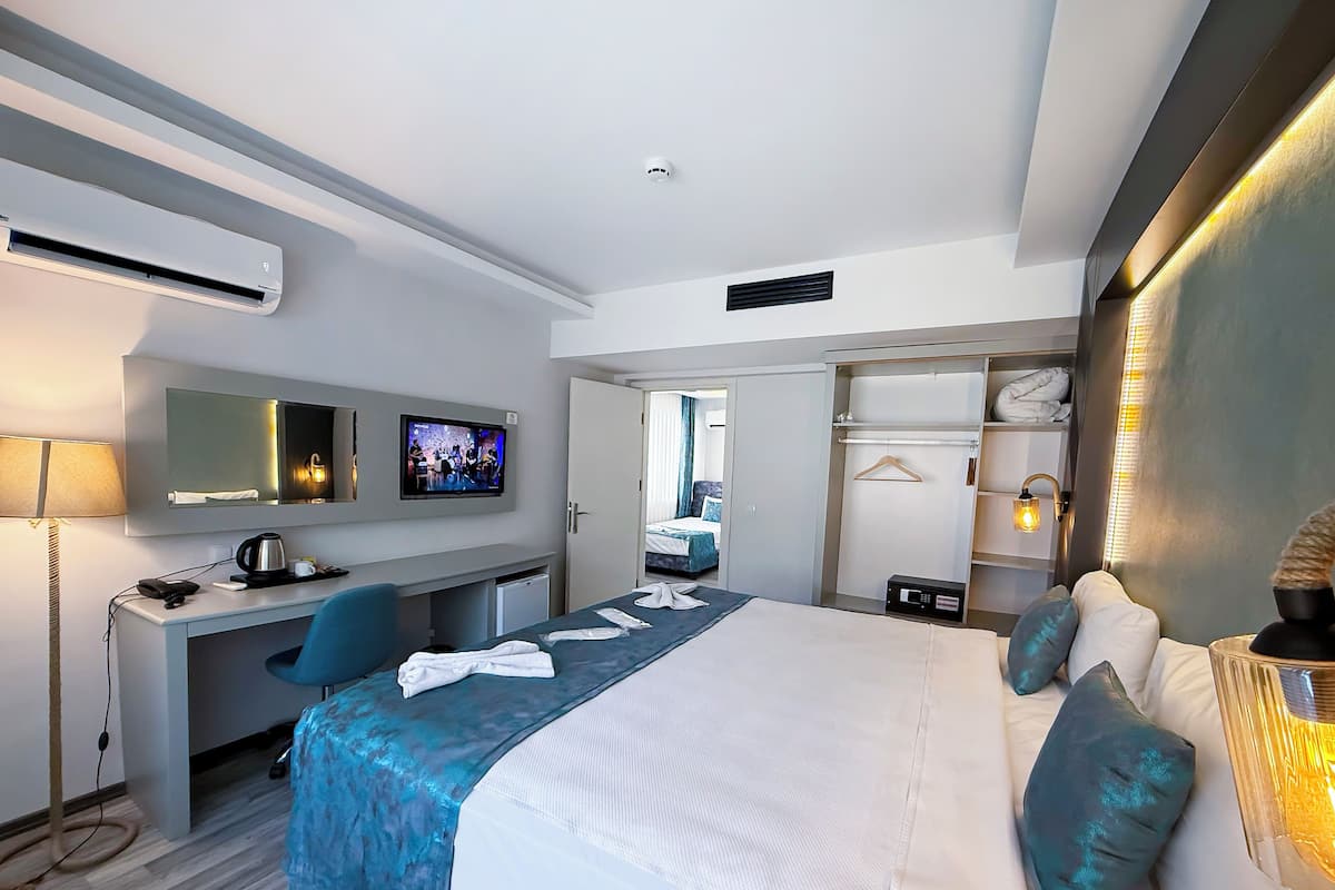 A hotel room with a bed, a desk, a TV, a wardrobe, and a bathroom visible through an open door.