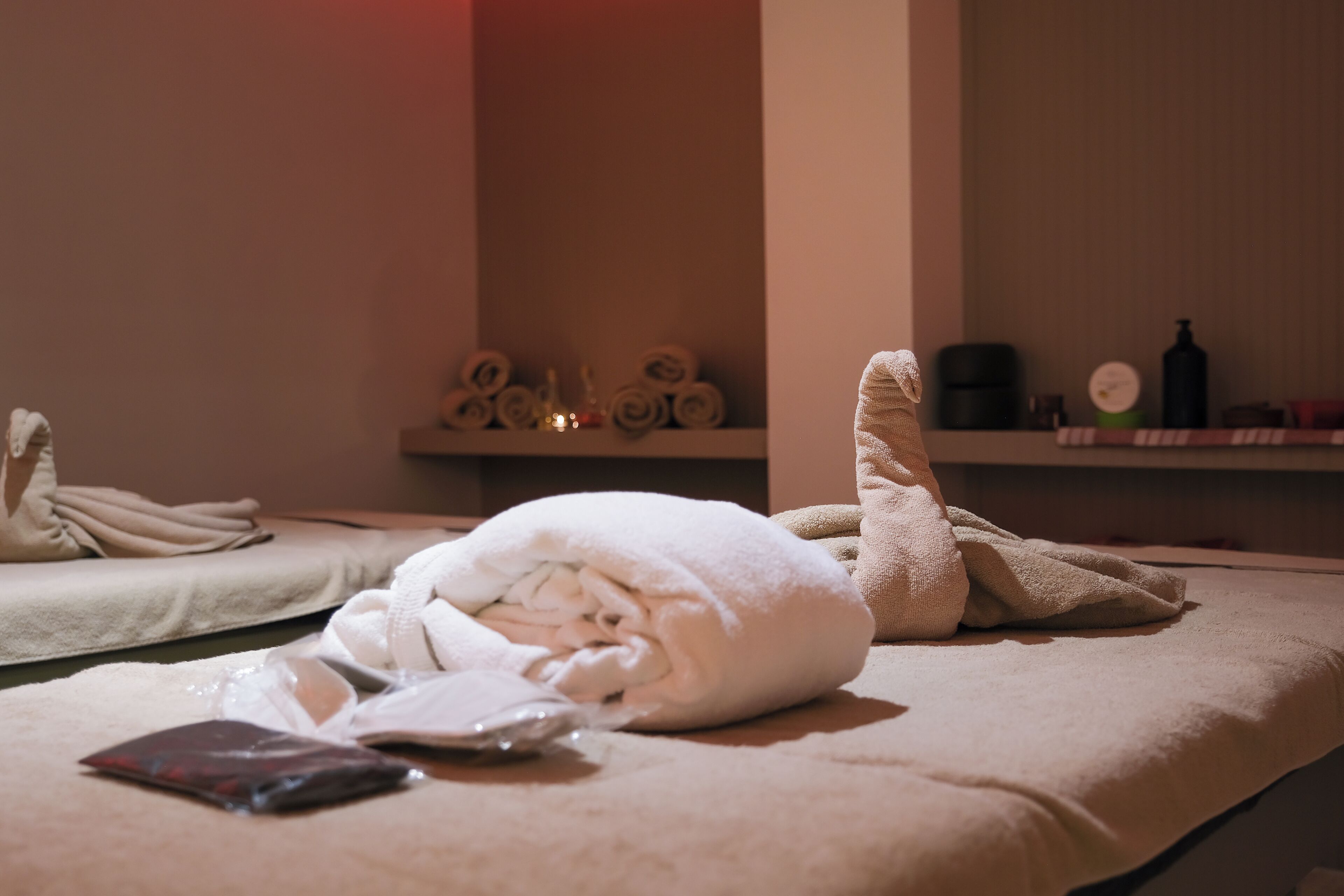 Un cuarto de spa con toallas, una botella y un estante pequeño con artículos de aseo.