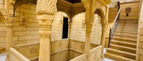 A traditional, ornately carved wooden structure with a marble floor, likely a private room or suite within a hotel.