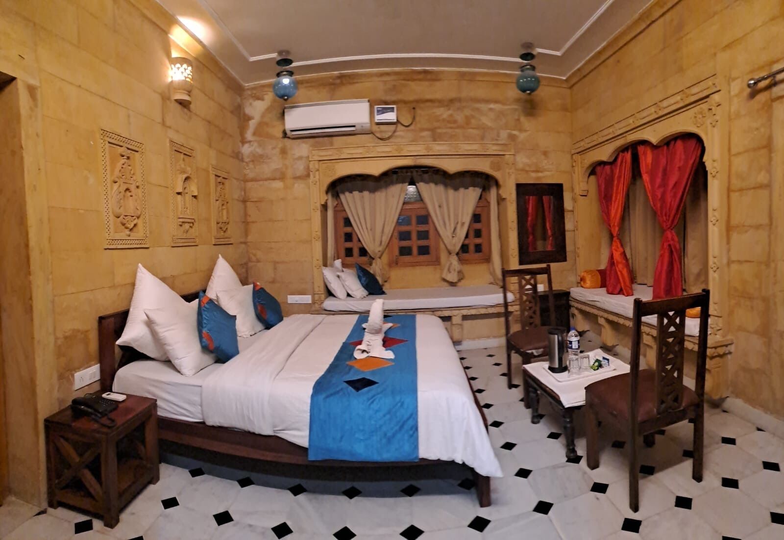 A hotel room with a large bed, a bedside table, a chair, and a desk.