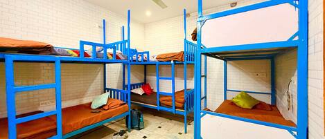 Un dormitorio con literas, ventilador de techo y piso de baldosas.
