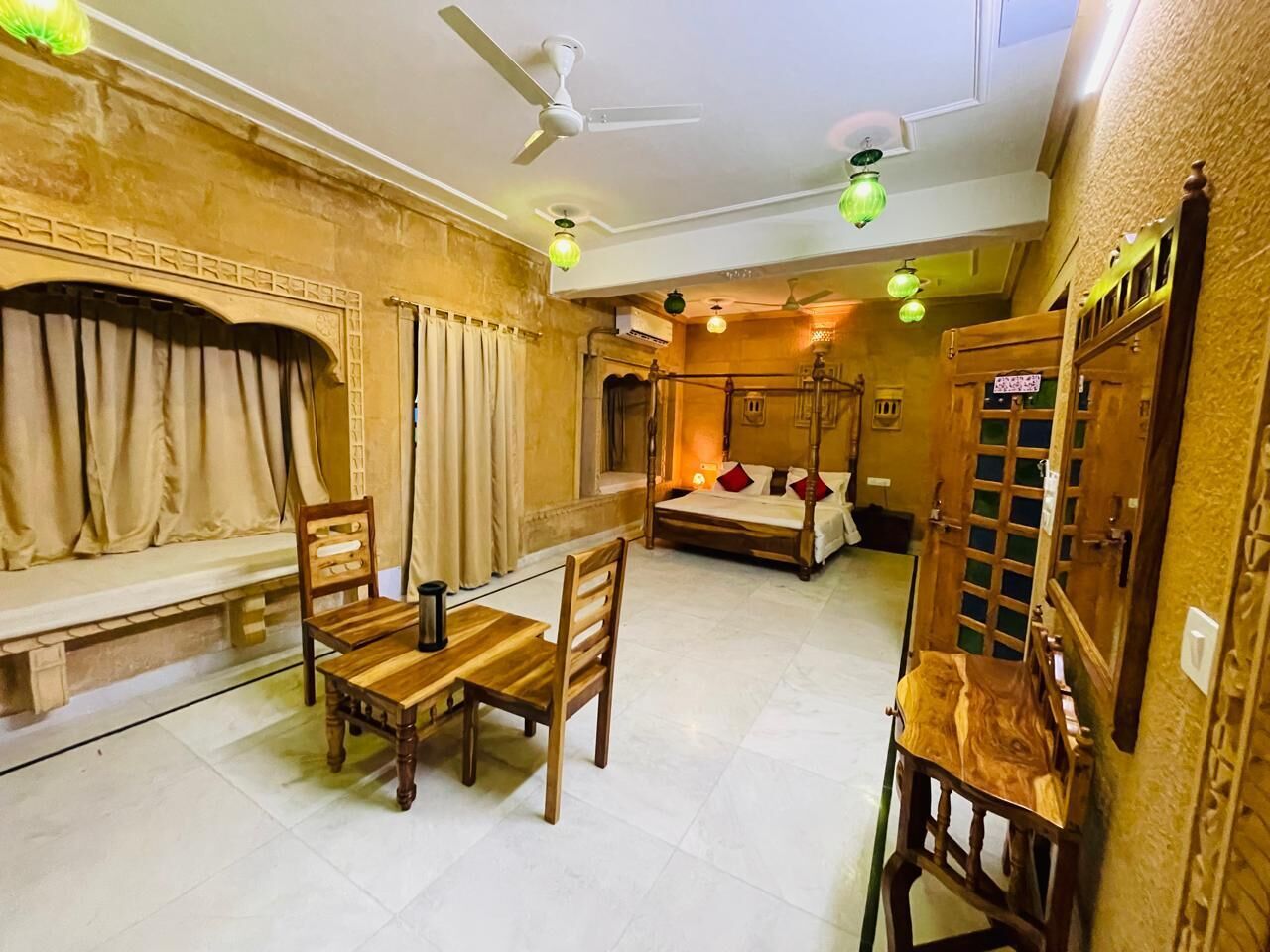 A room with a bed, a dining table with chairs, a bench, and a ceiling fan.