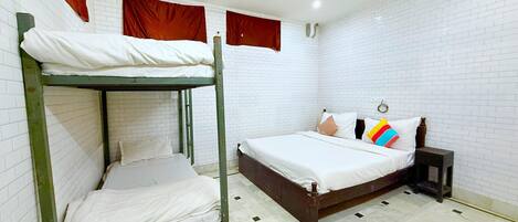 Una habitación con literas, una cama individual, una mesita de noche y un ventilador de techo.