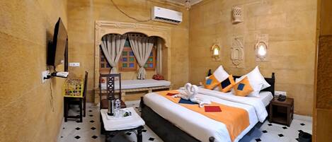 A hotel room with a bed, bedside table, chair, and a small desk with a chair.