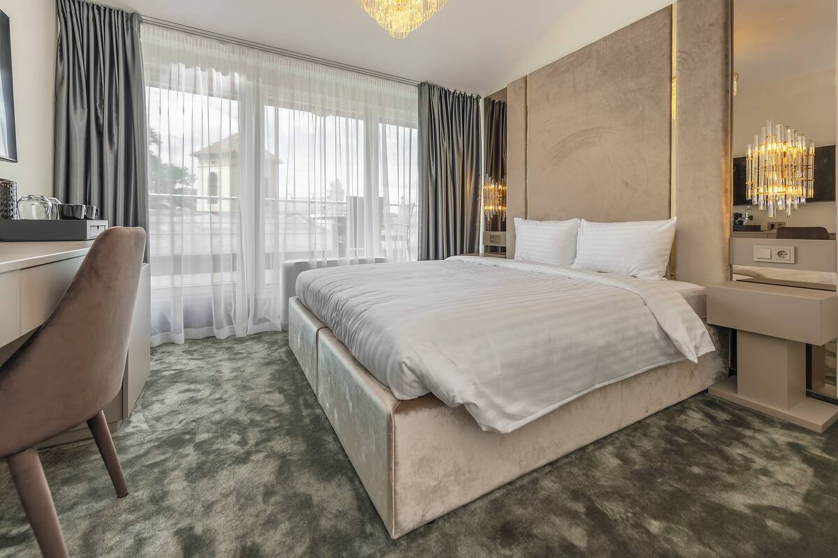 A modern hotel room with a large bed, a desk, and a chair.