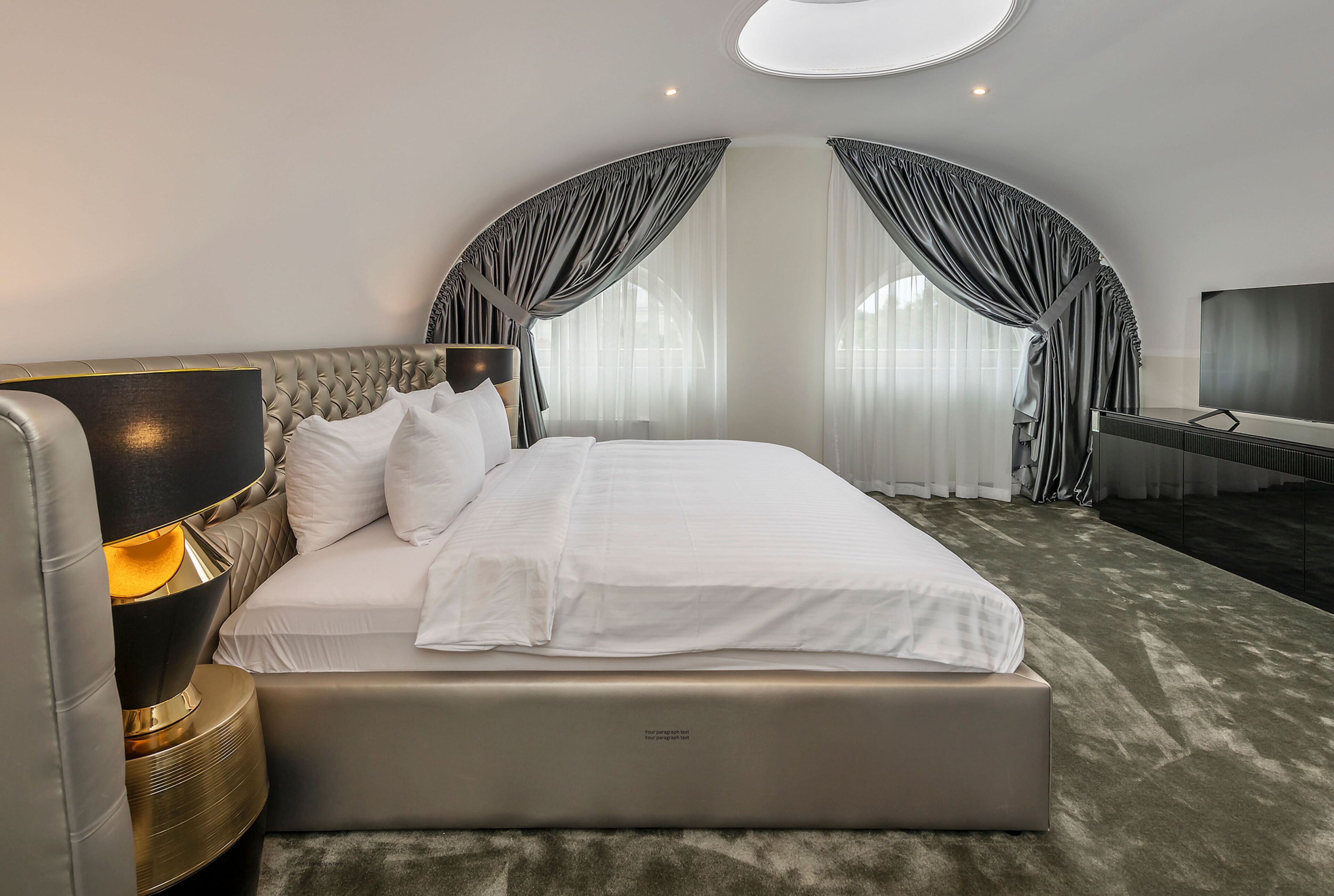 A modern hotel room with a large bed, a bedside lamp, and a television.