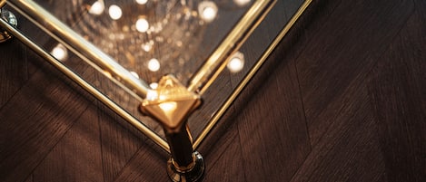 Detalhe de canto em metal dourado no chão de madeira.
