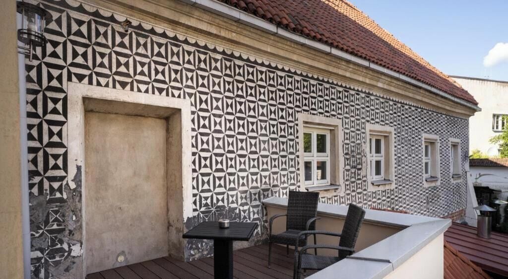 Un bâtiment doté d’une façade extérieure à motifs, d’une porte, de fenêtres et d’un petit espace extérieur aménagé avec une table et des chaises.