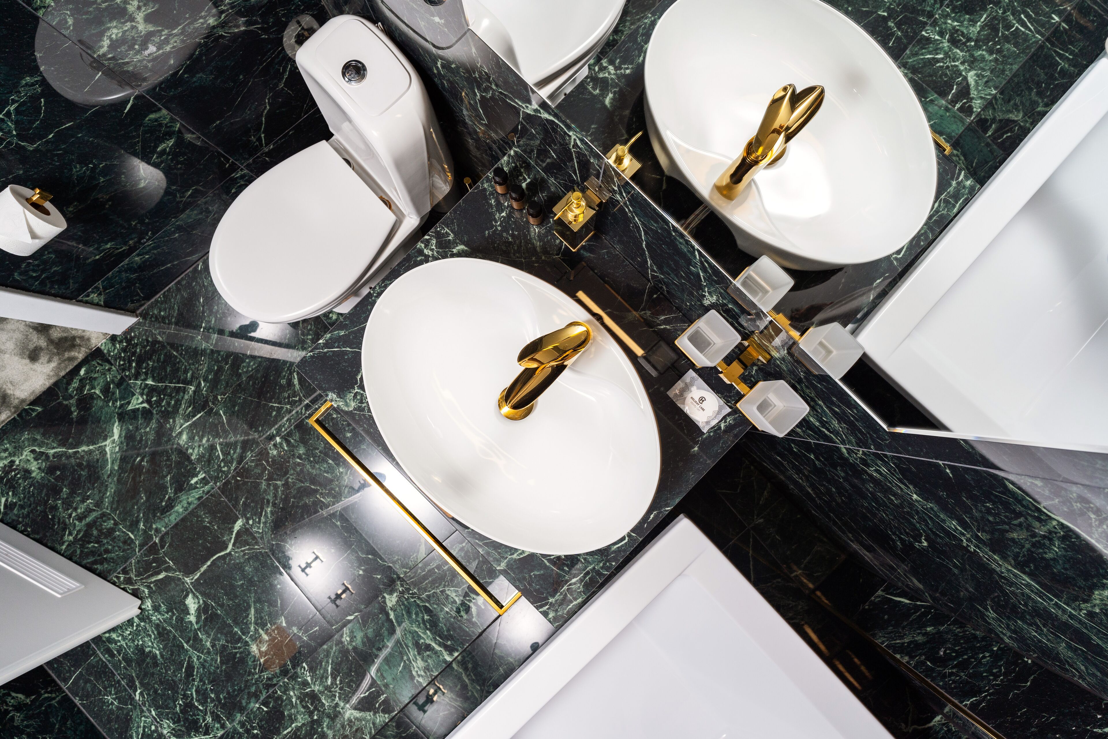 A modern bathroom with two sinks, a toilet, and a bathtub.